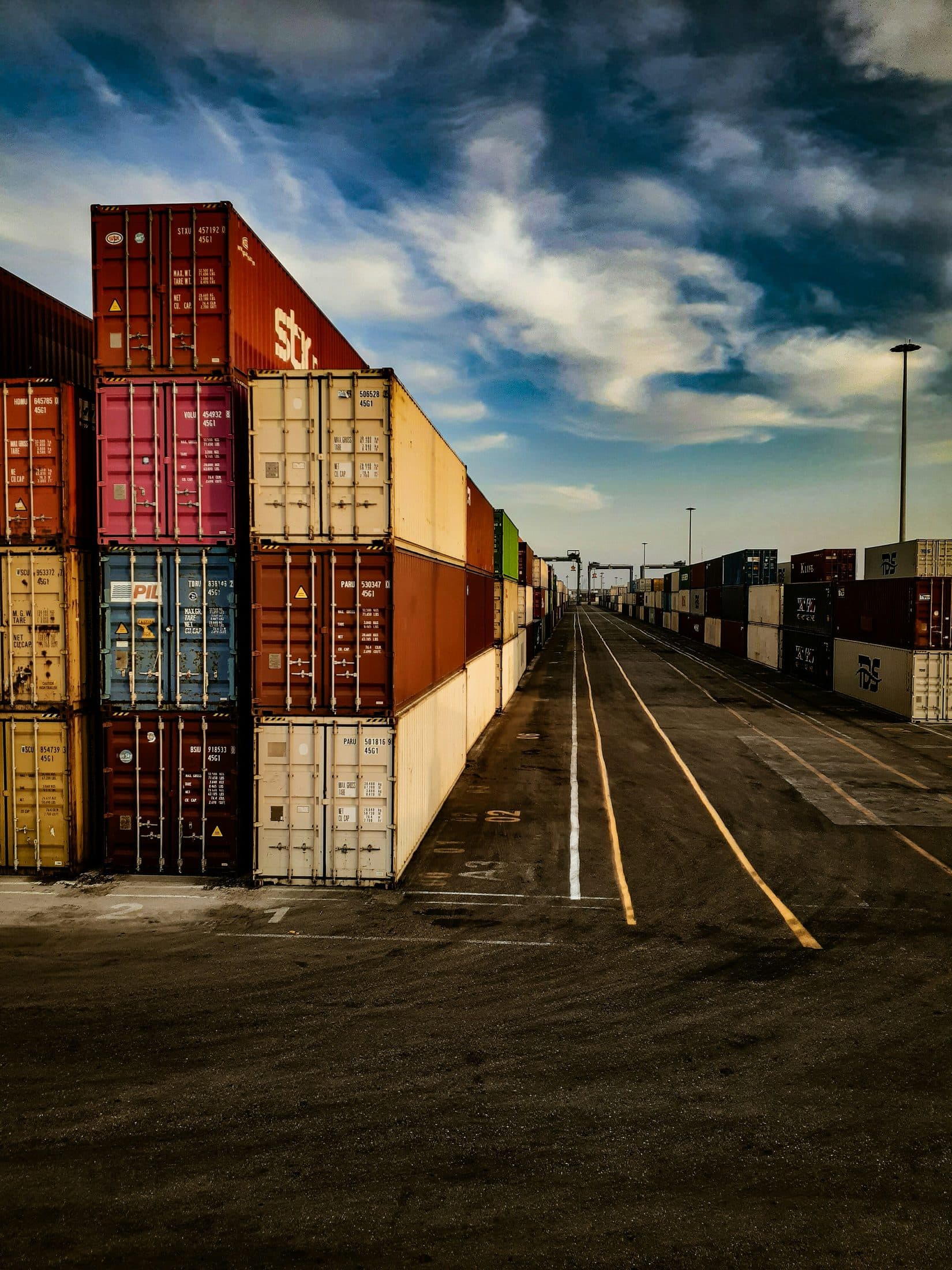 A container yard road stretching toward the horizon under a dramatic sky